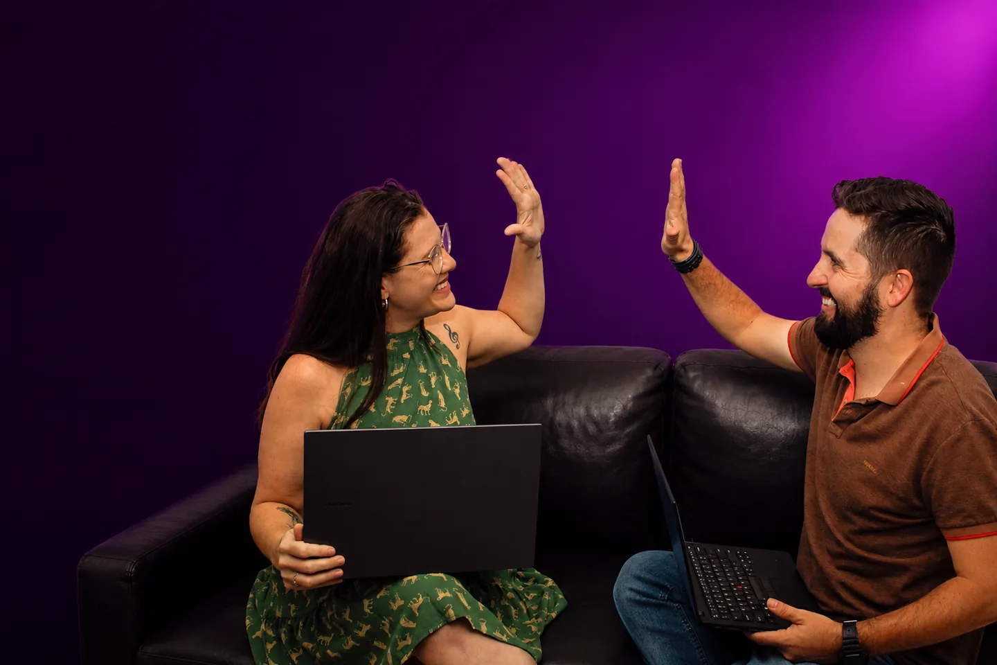 Flora e Lucas, professores da Witty, celebrando em aula ao vivo com laptops